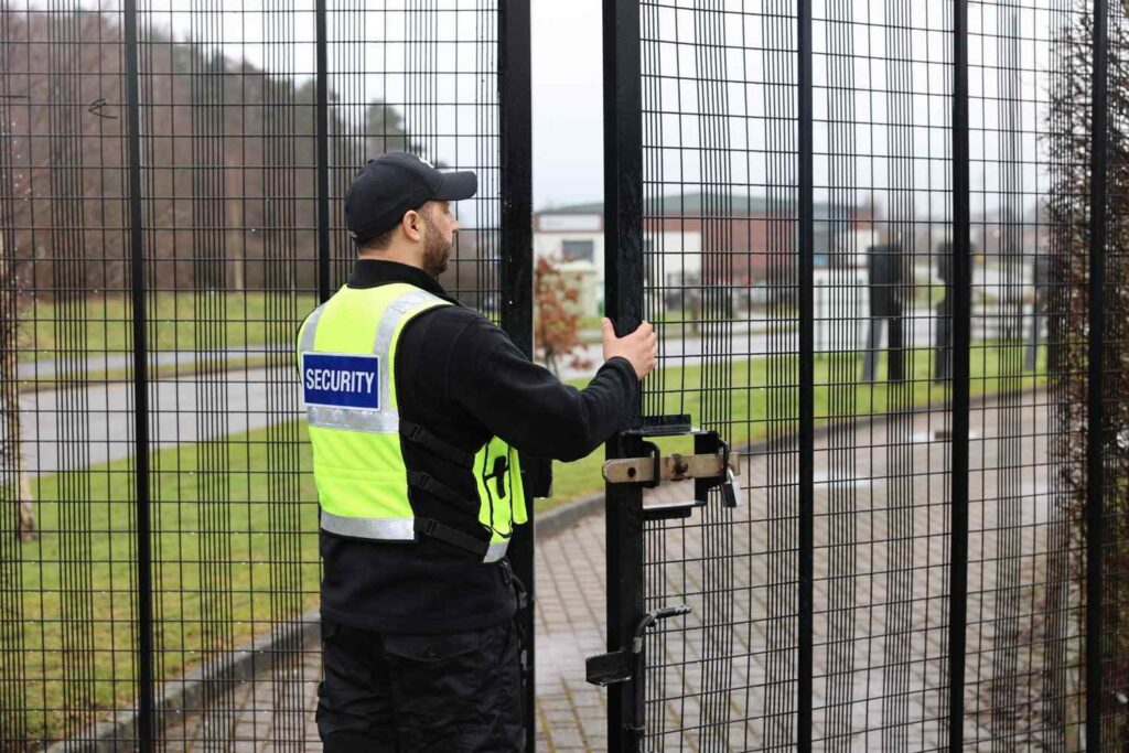 A professional and trained guard securing a vacant building in the UK with steel gates and reliable locks for vacant property security.