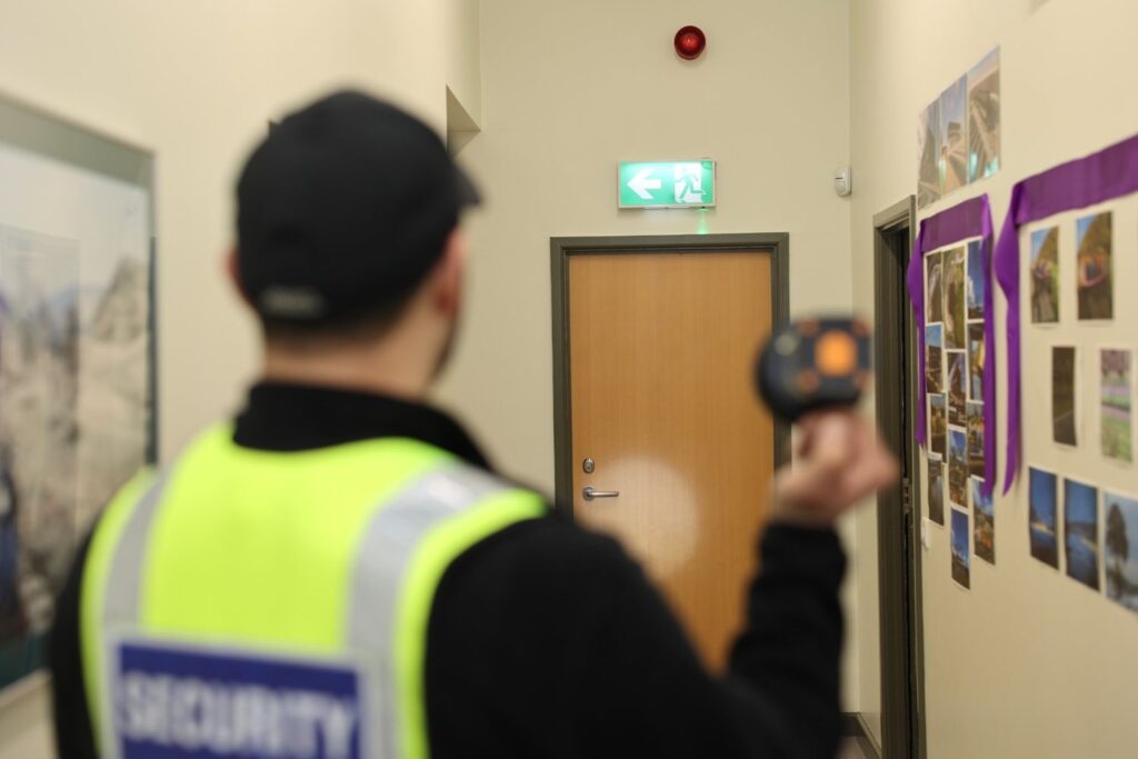 Uniformed security patrol officer in a commercial building in the UK during a site visit, inspecting the key areas for safety and security concerns.