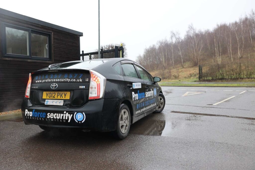 Marked mobile patrol security vehicle parked near the entrance of a warehouse facility carrying out the routine patrol duties for crime deterrence.