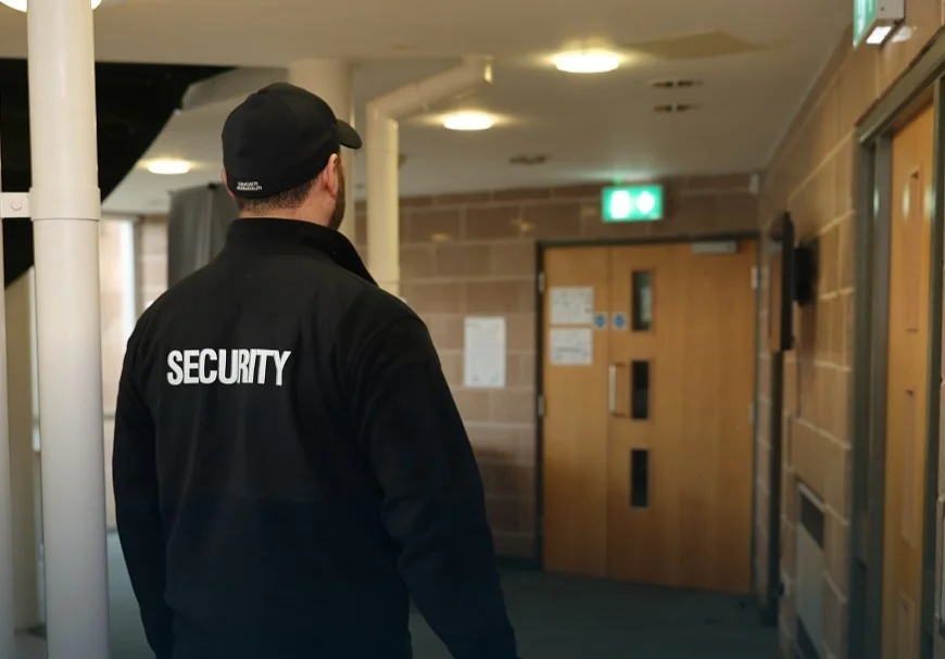 Trained waking watch personnel patrolling the corridors of a high-rise residential building, checking for fire hazards and ensuring resident safety.